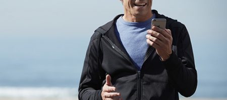 Homme utilisant des aides auditives connectées à son smartphone