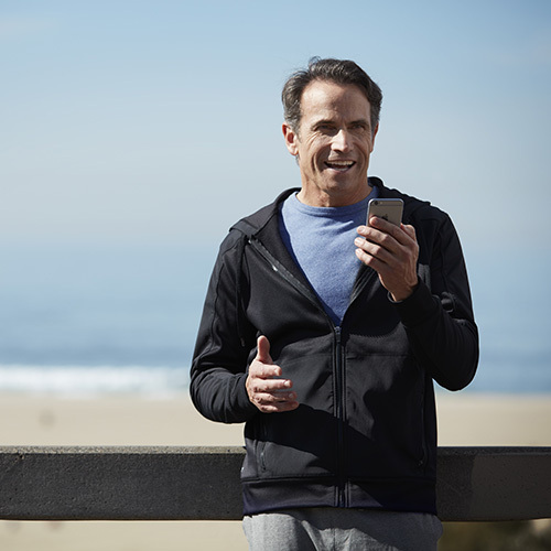 Homme utilisant des aides auditives connectées à son smartphone